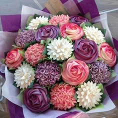 a bouquet of colorful flowers sitting on top of a purple and white table cloths