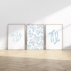 three framed art prints sitting on top of a wooden table next to a white wall