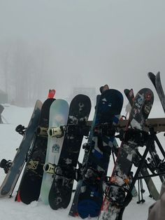 a pile of snowboards sitting on top of a snow covered slope in the snow