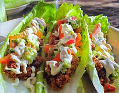 two lettuce wraps filled with taco meat and toppings on a plate