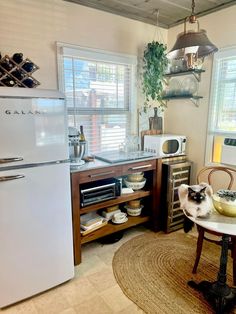 a small kitchen with an old fashioned refrigerator and table in the corner, next to a window