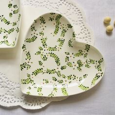 two heart shaped dishes sitting on top of a white doily covered tablecloth next to each other