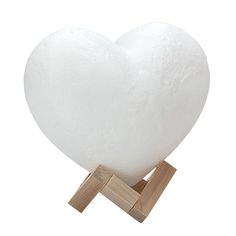 a large white heart shaped lamp on a wooden stand with a wood holder for it