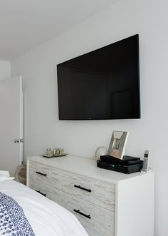 a flat screen tv mounted on the wall above a bed