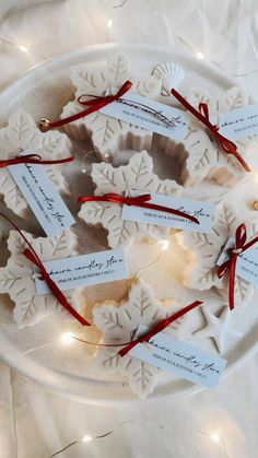 white snowflake ornaments with red ribbon and tags on a platter decorated with christmas lights