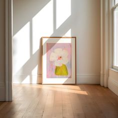 an empty room with a painting on the wall and sunlight coming in through the windows