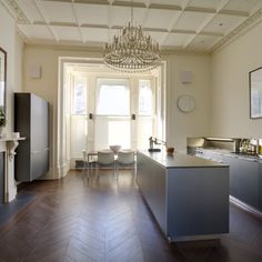 a large kitchen with an island and chandelier hanging from it's ceiling