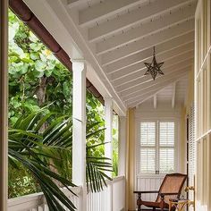 a porch with a chair and potted plant on the side walk next to it