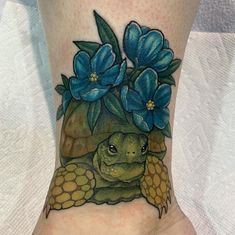 a close up of a person's foot with a turtle and flowers on it