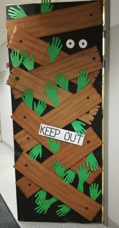 a door decorated with green handprints and cutouts that says keep out on it