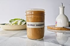 a jar of peanut butter sitting on top of a table next to a bowl of food