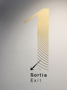 the logo for sortie exit is shown in gold and silver on a white wall