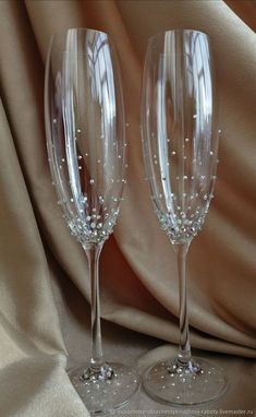 two wine glasses sitting next to each other on top of a cloth covered tablecloth