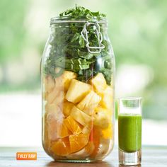 a mason jar filled with fruit and veggies next to a green smoothie