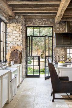 an open kitchen with stone walls and doors leading into the dining area, along with a large window