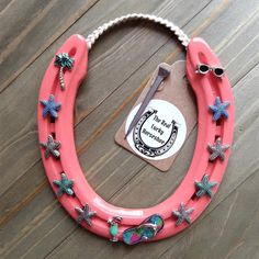 a pink horseshoe with blue and silver stars around it on a wooden table next to a pair of sunglasses