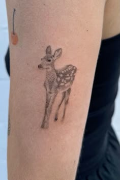 a woman's arm with a small deer tattoo on it