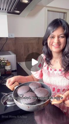 a woman holding a pan filled with cupcakes