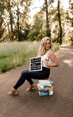 a woman sitting on top of a pile of books holding a sign that says, i am not afraid to read