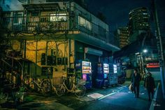 two people are walking down the street at night