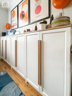 a kitchen with white cabinets and pictures on the wall above it, along with rugs