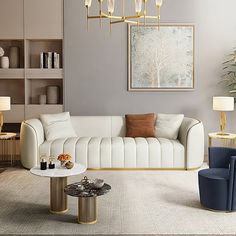 a modern living room with white furniture and gold accents on the walls, along with two blue chairs