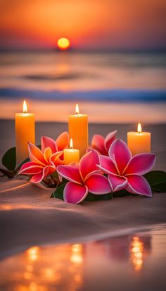 three candles with flowers on the beach at sunset