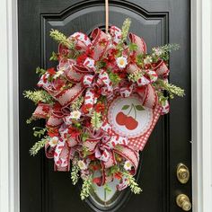 a red and white wreath with an apple on it hanging from the front door,