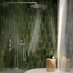 a bathroom with green tiles and a shower head