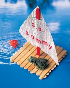 there is a small toy boat on top of some sticks in the water with a red fish