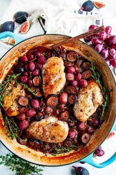 a pan filled with meat and grapes on top of a table