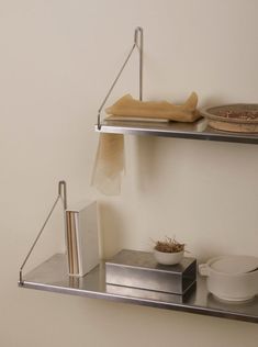 two metal shelves holding books, bowls and other items on top of eachother