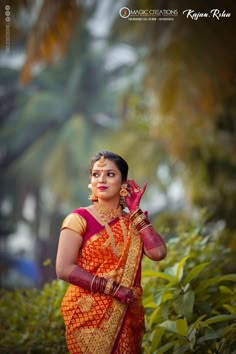 a woman in an orange and red sari holding her hands up to her face