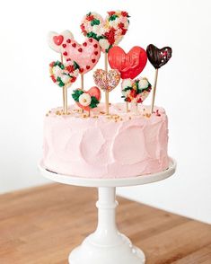 a pink cake topped with lots of hearts and lollipops