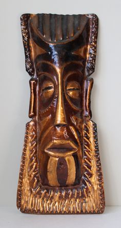 a wooden mask on display against a white wall