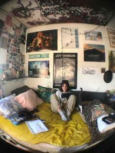 a man sitting on top of a bed in a room filled with pictures and posters