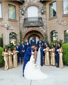 a bride and groom kissing in front of their wedding party at the entrance of a mansion