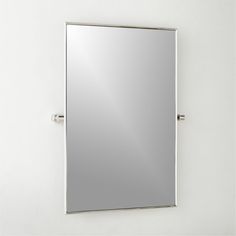 a mirror mounted to the side of a white wall next to a metal bar handle