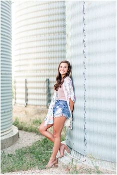 a young woman leaning against a silo