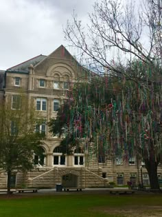 an old building with lots of colorful streamers hanging from it's roof and trees in the foreground