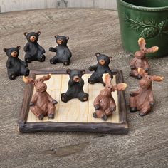 small figurines of bears playing chess on a wooden table next to a potted plant