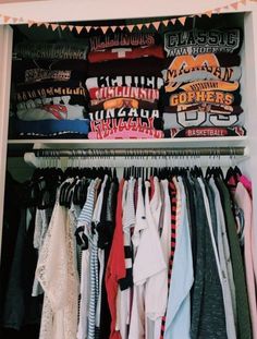 an open closet filled with clothes and t - shirts