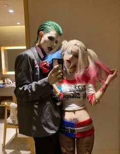 a man and woman dressed up as the joker and harley in front of a mirror