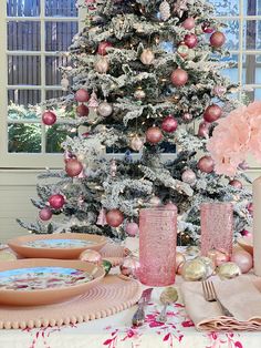 a decorated christmas tree in the corner of a dining room with pink and gold decorations