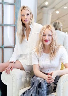 two beautiful women sitting on top of white chairs in front of a store display window