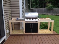 an outdoor bbq grill built into the side of a house with wooden decking