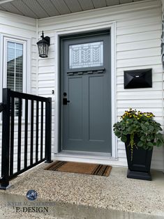 a gray front door on a white house with black iron railings and potted plants