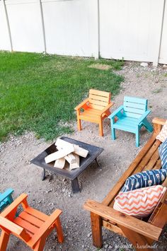 an outdoor fire pit surrounded by wooden chairs and lawn furniture in the back yard area