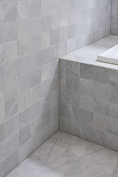 the corner of a white tiled bathroom with no shower curtain