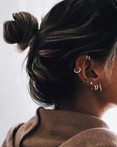 a woman with her hair in a bun and earrings on top of her head, looking off to the side